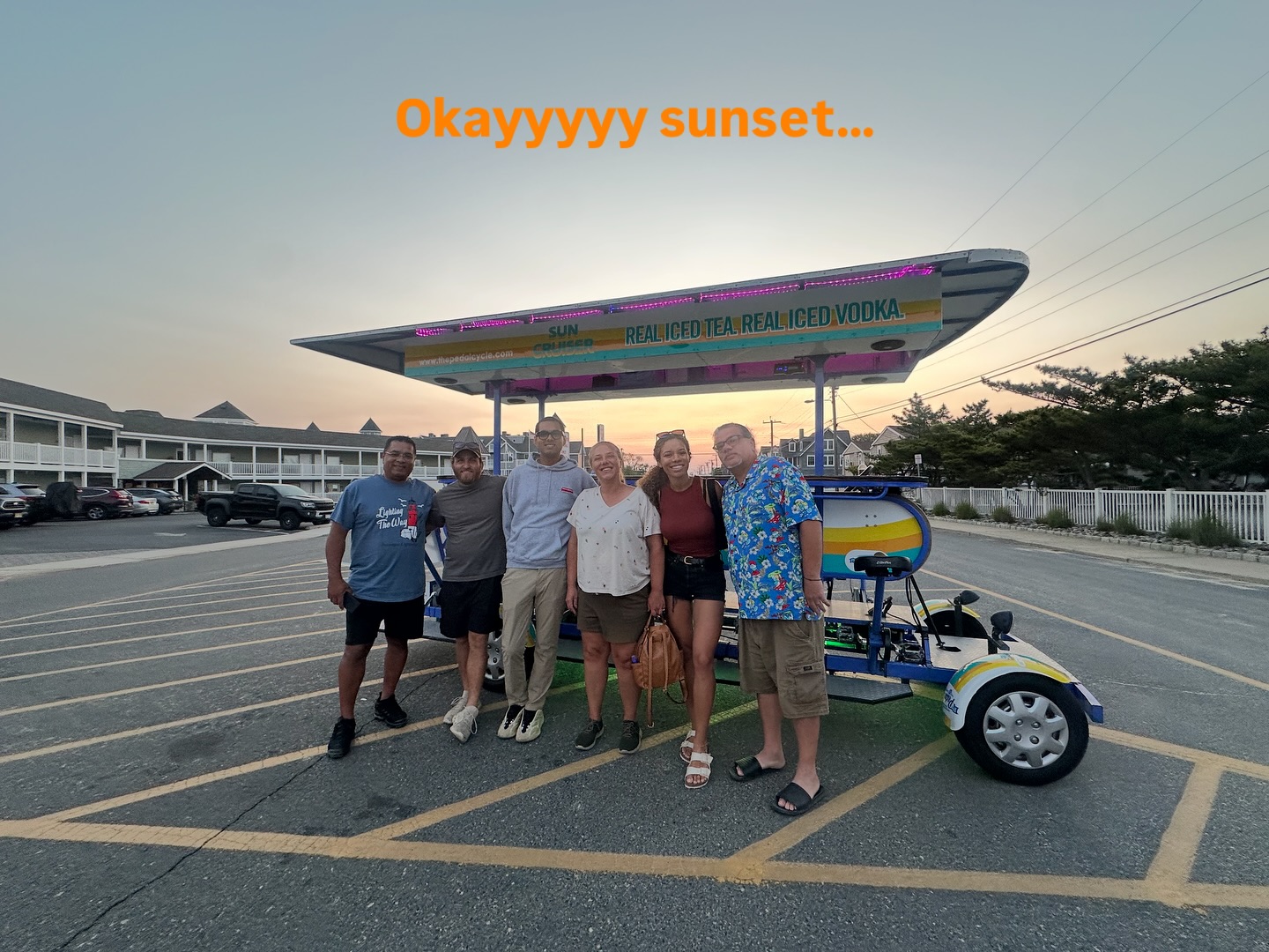 Group of people posing in front of a parked pedicab at sunset with text 'Okayyyyy sunset' above.