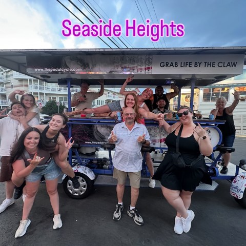 Group posing with a cycle cart labeled 'Seaside Heights' on a street.