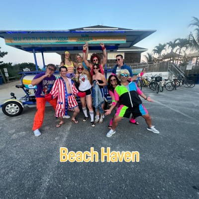 Group posing in colorful outfits in front of pedal bike at Beach Haven.