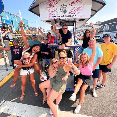 Group of people posing joyfully around a pedal bike on a street.