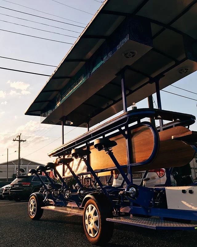 A pedal-powered vehicle with seats and canopy parked at sunset, seen from a low angle.