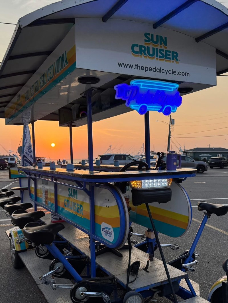 Pedal-powered party bike at sunset near beach buildings.